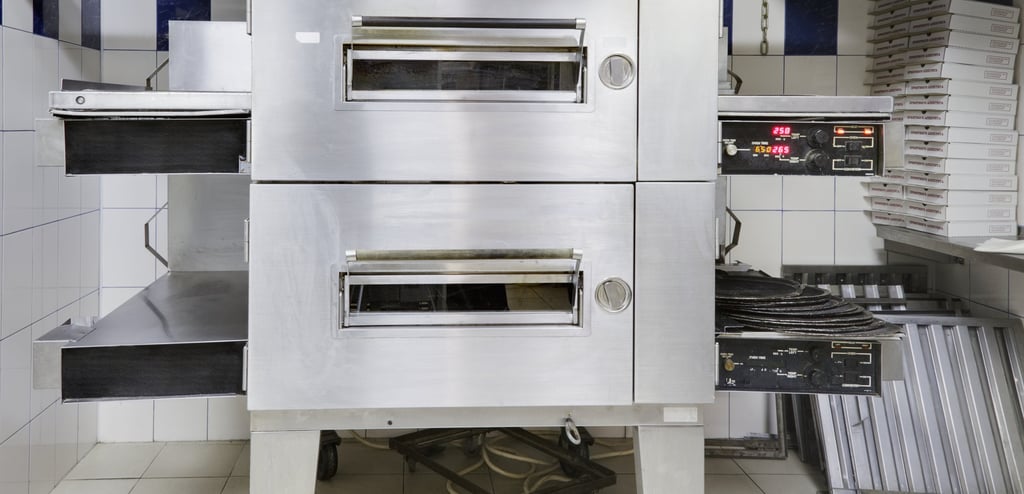 A stainless steel double-deck pizza oven with trays extended and control panels showing temperature settings.