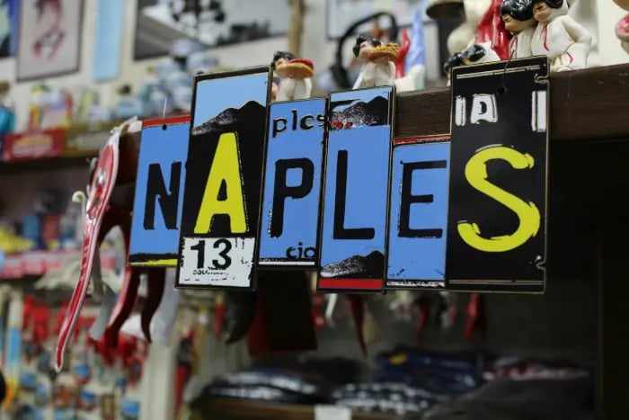 Insegna decorativa con la scritta “Naples” in un negozio di souvenir, usata come immagine hero per l