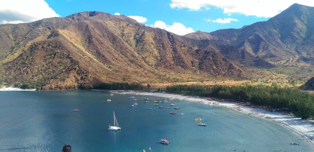 Stunning white sand beach in Zambales with a boat and mountain views, featured by Zam Realty.