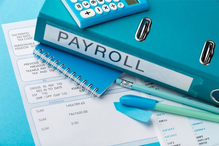 Payroll documents, calculator, and notebook on a desk representing employee salary management and accounting process.
