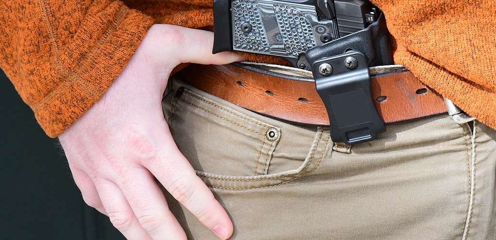gun being concealed inside the waist band of a pair of pants