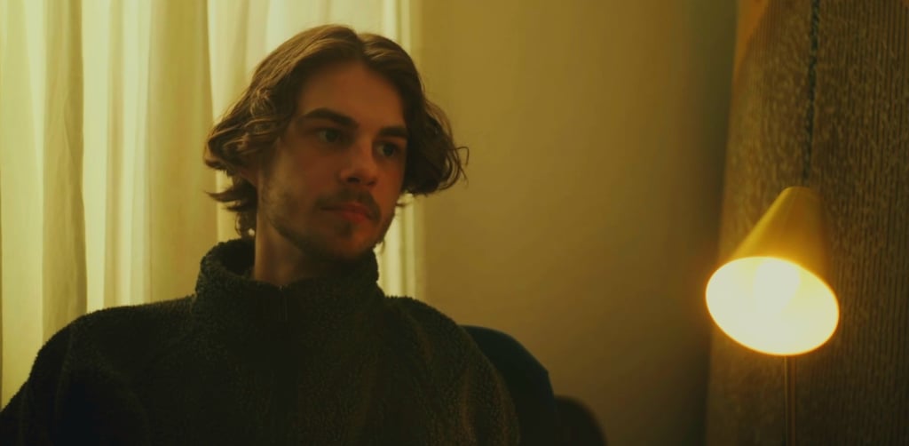a man in a black sweater and a light bulb on a lamp