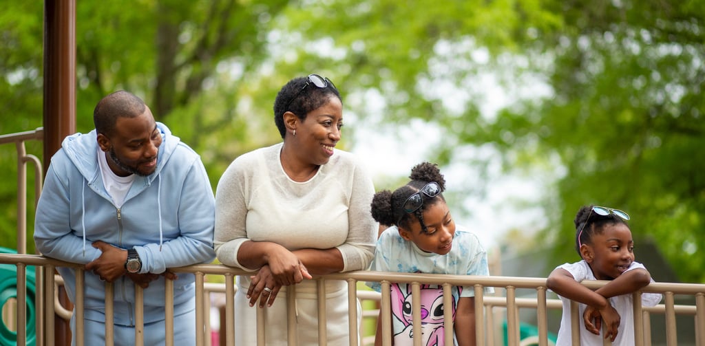 mom and dad with two children smiling and enjoying a day at the park with children