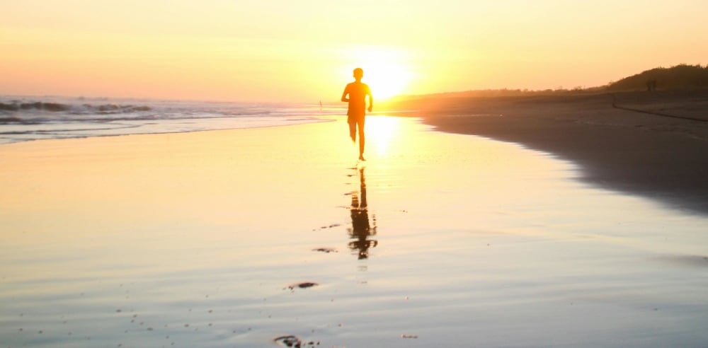 a person walking on a beach at sunset