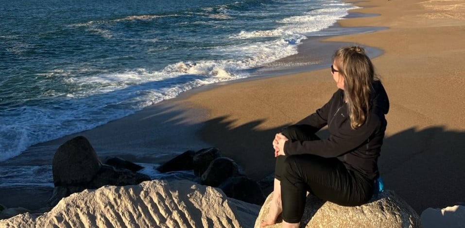 person sitting on the beach watching the waves