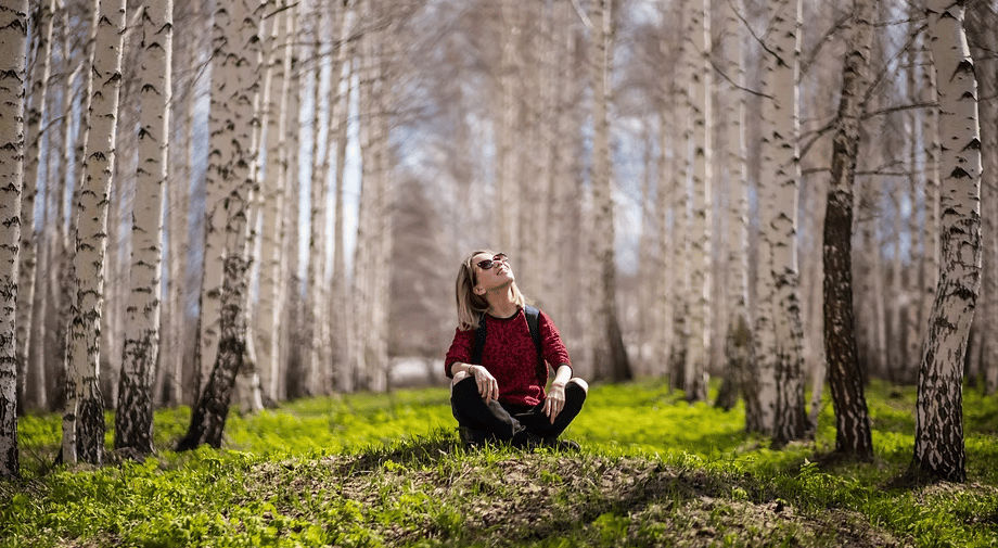 A woman sitting surrounded by a forest.