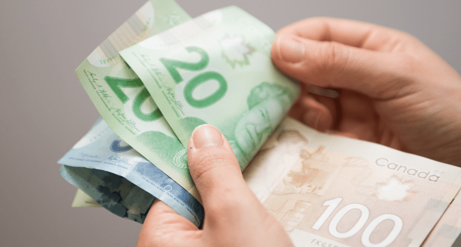 a person holding a stack of cash and a stack of Canadian dollarbills