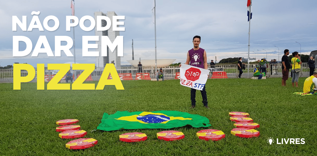 homem em gramado verde segurando cartaz escrito stop pizza stf em imagem com logo do livres