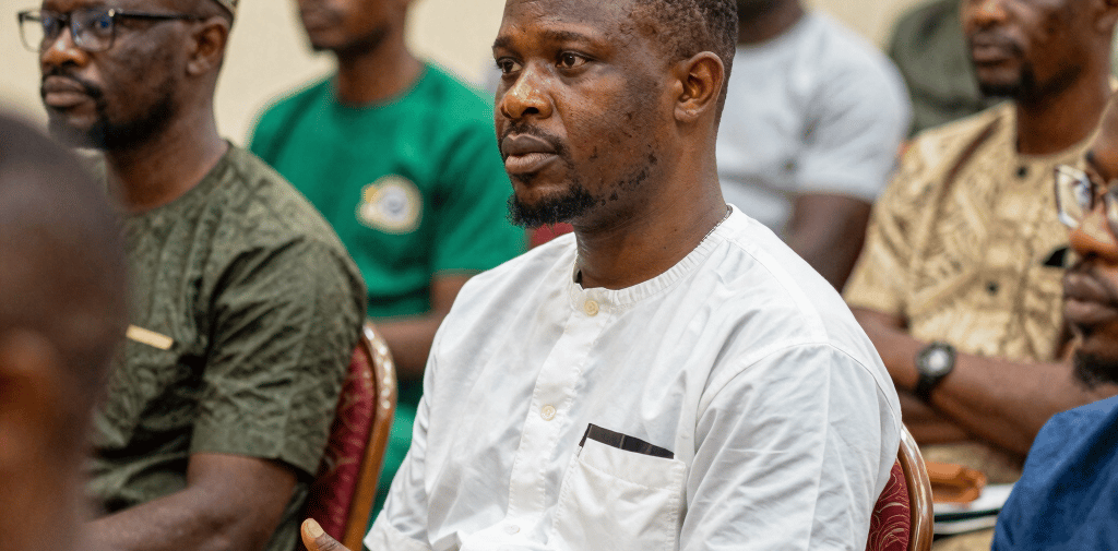 Diverse people building a foundation beneath a glowing document amidst city ruins and stone pillars.