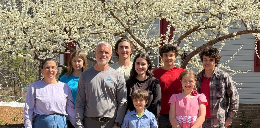 Family team members with a blooming plum tree behind them.