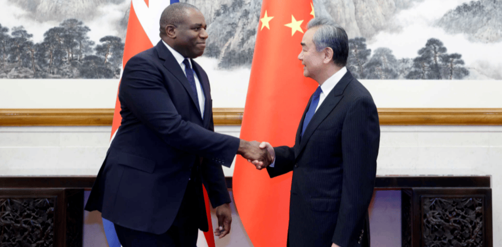 two men shaking hands in front of a chinese flag
