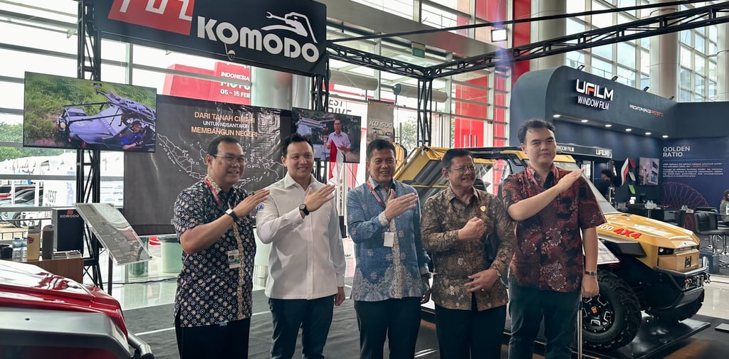 Moreno Soeprapto posing with a Fin Komodo off-road vehicle at an automotive exhibition booth.
