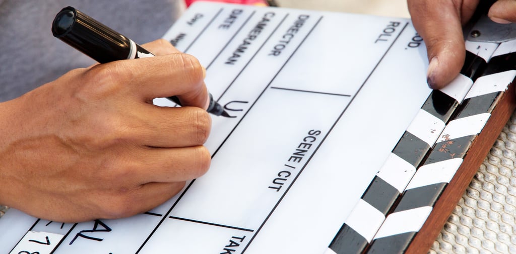 a person holding a pen and writing on a clapperboard