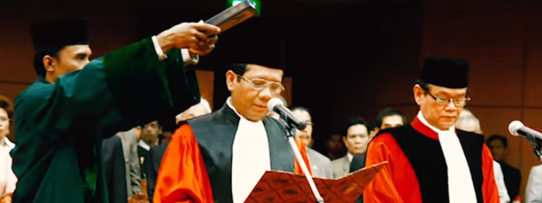 a man in a suit and tie is holding a microphone