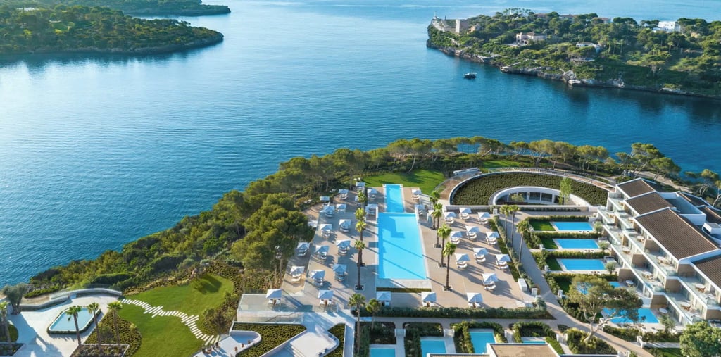 Aerial view of a luxury coastal resort in Mallorca with swimming pools and turquoise ocean views.