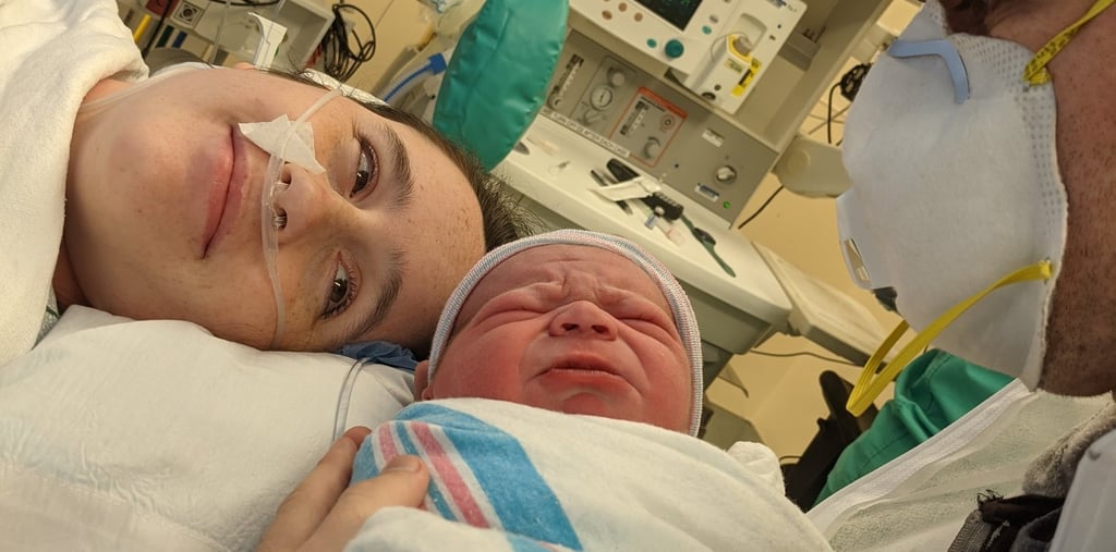 Image of mom and baby while mom is being patched up after a C-section.
