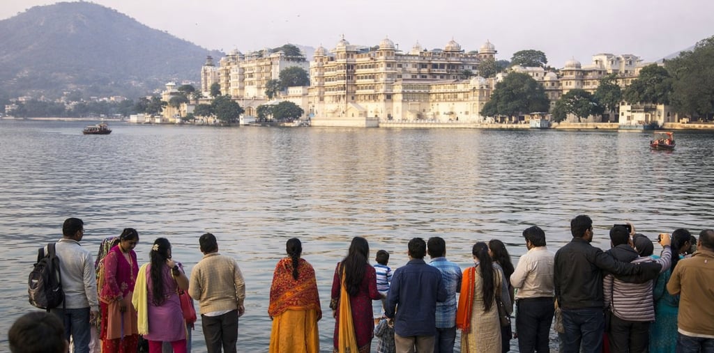 Tourists viewing the historic Udaipur City Palace across Lake Pichola in Rajasthan, India.
