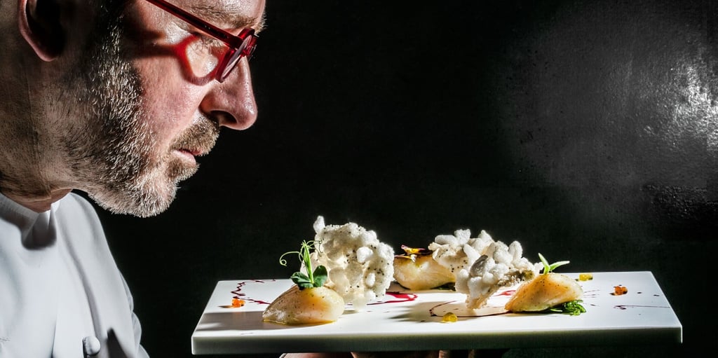 a man in a white shirt and glasses is holding a plate with food