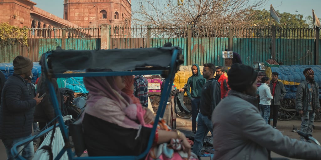 Crowded Old Delhi street with rickshaws and pedestrians near Jama Masjid.