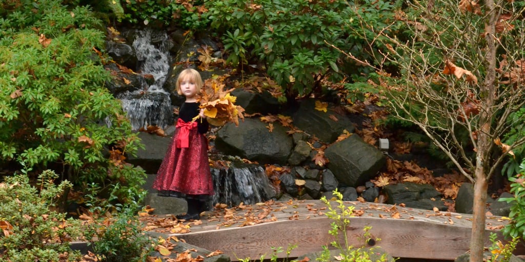 a little girl in a red dress holding a leaflet