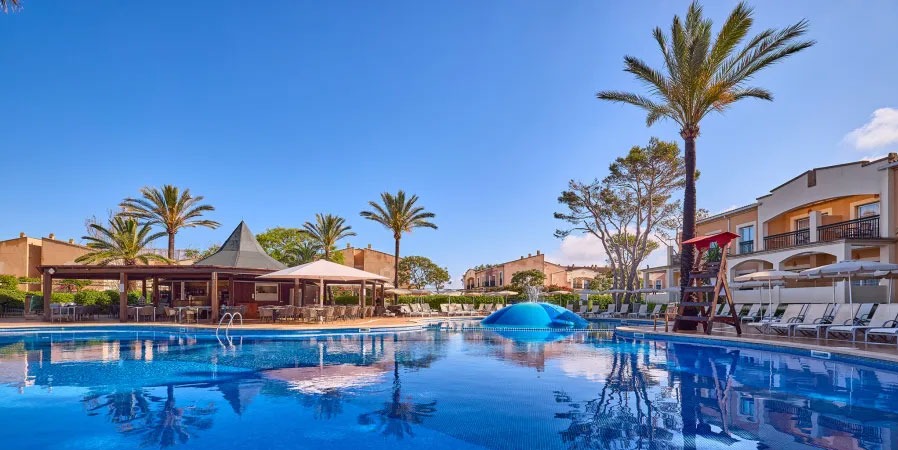Large Swimming Pool with Palm Trees and Blue Sky at Zafiro Menorca