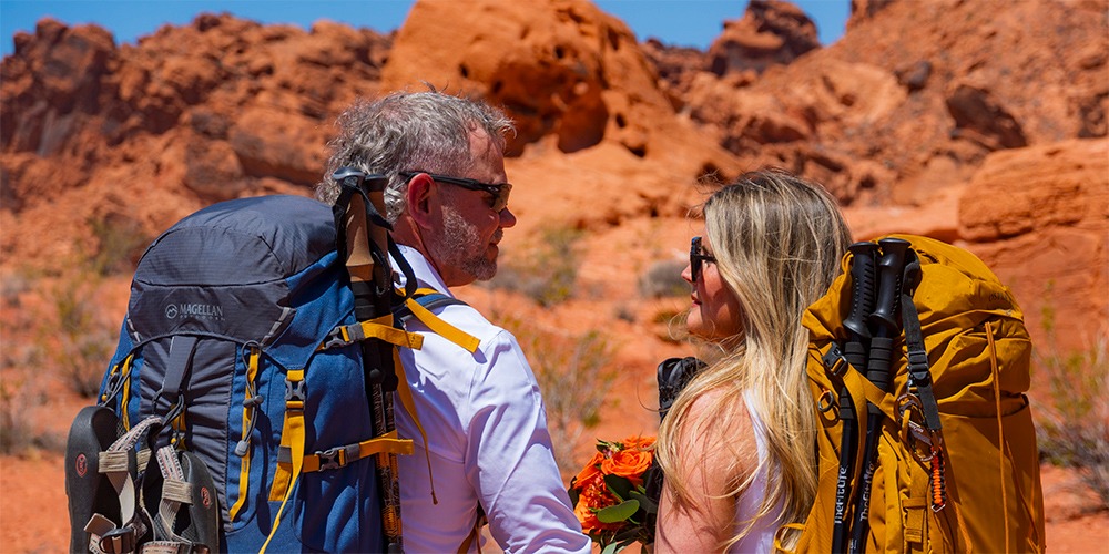 A couple with hiking backpacks and trekking poles at Valley of Fire State Park.