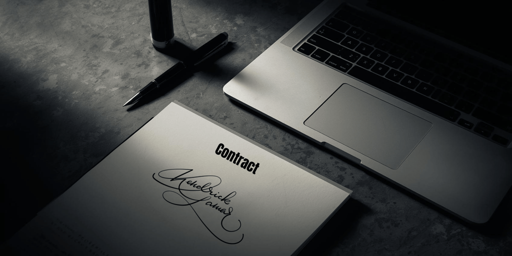 Signed business contract document with a fountain pen and laptop on a dark desk.