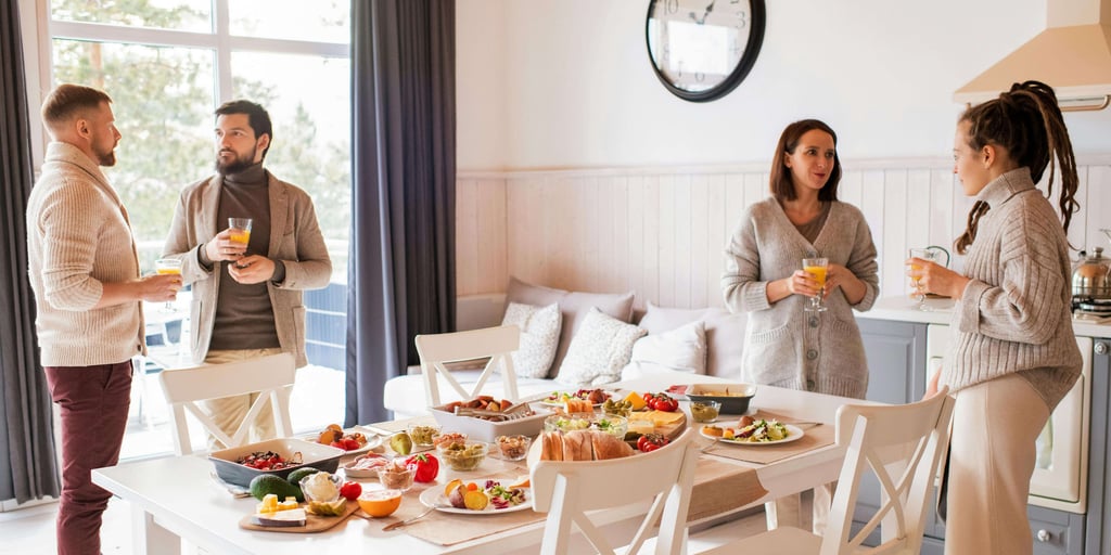 a group of people standing around a table with food
