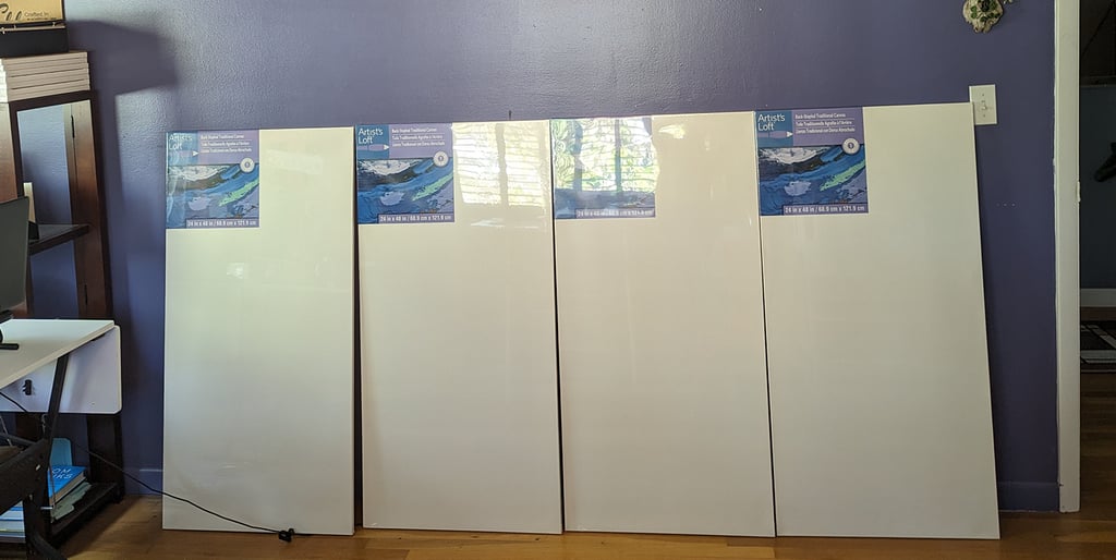 Four 2-foot by 4-foot canvas panels side by side ready to be attached to an empty wall for painting.