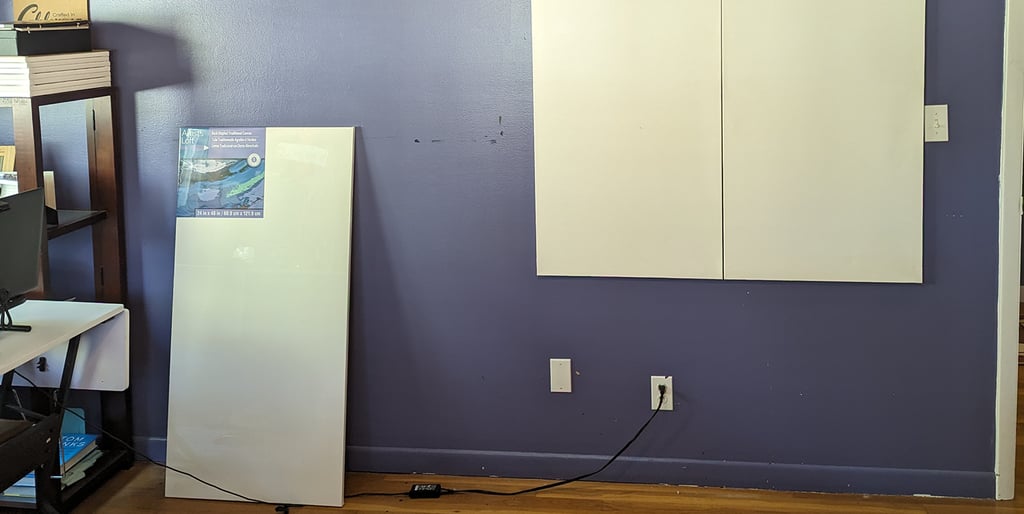 Stretched canvas panels being attached to an art studio wall with Velcro tabs.