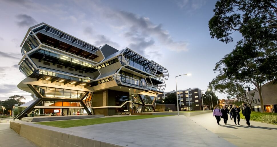 Monash University modern building with glass facade illuminated at dusk, representing academic excel