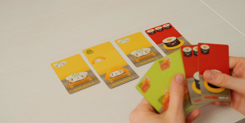 Rankoje laikomos ir ant stalo padėtos Sushi Go žaidimo kortos