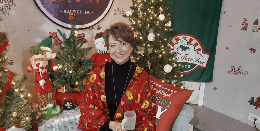 a woman in a red jacket is holding a glass of beer in a seasonal setting