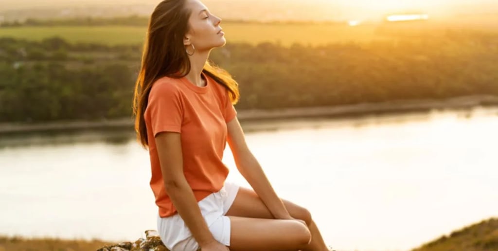Mulher sentada ao ar livre, olhos fechados, respirando fundo e relaxando em um momento de tranquilid