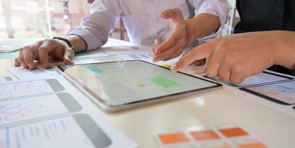 Dizajneri i projektni menadžeri analiziraju wireframe aplikacije na tabletu – primena Agile metodolo