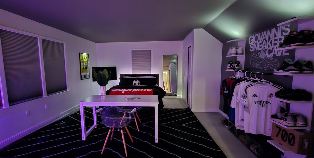 Modern bedroom featuring LED ambient lighting, a sneaker display shelf, and a white desk with clear chairs.