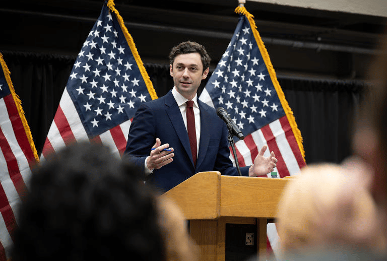 a man in a suit and tie is speaking into a microphone