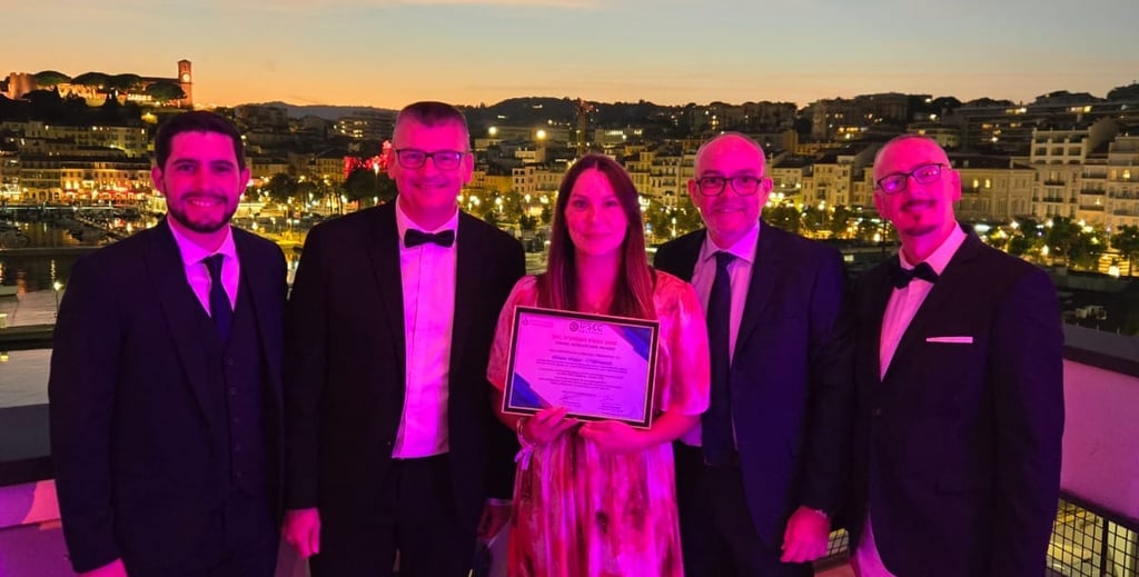 Professional group holding an award certificate on a balcony overlooking a sunset cityscape.