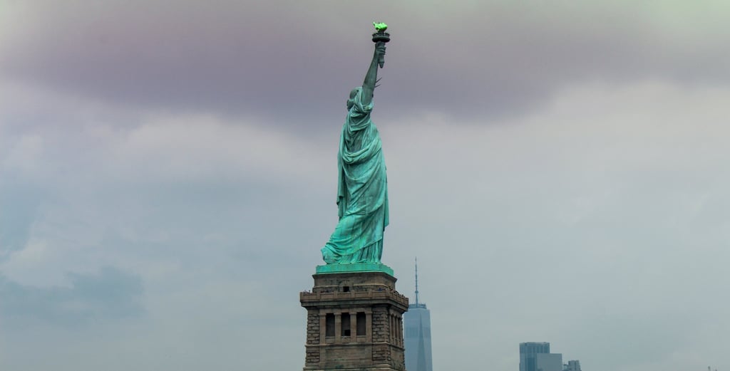 statua della libertà con piedistallo in pietra e sfondo di cielo plumbeo