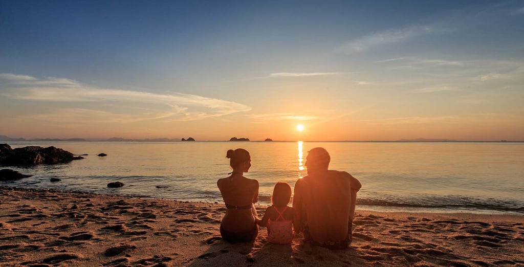 Family sitting together on beach at sunset during Koh Samui photoshoot