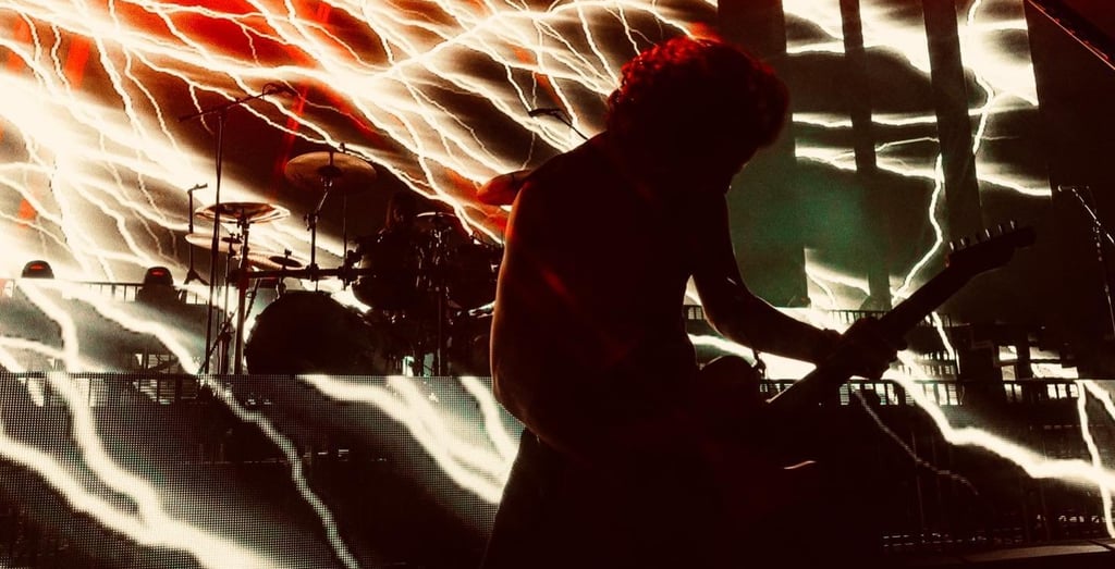 Groupe de métal Gojira qui agite les cheveux devant un visuel d'éclairs