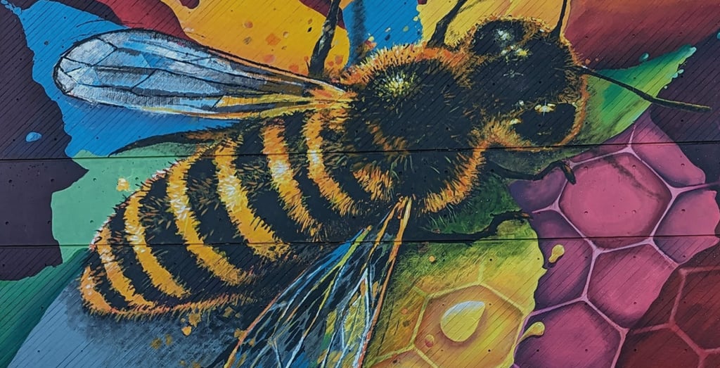 Vibrant honey bee mural painted on wood featuring a honeycomb pattern and colorful street art.