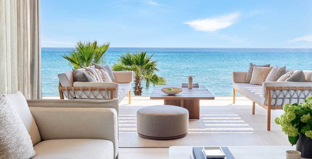 Luxury outdoor patio furniture on a balcony overlooking the turquoise ocean and palm trees.