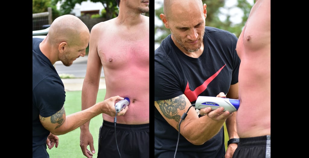 Entrenador experto midiendo grasa corporal con ultrasonido Bodymetrix en el abdomen del cliente.