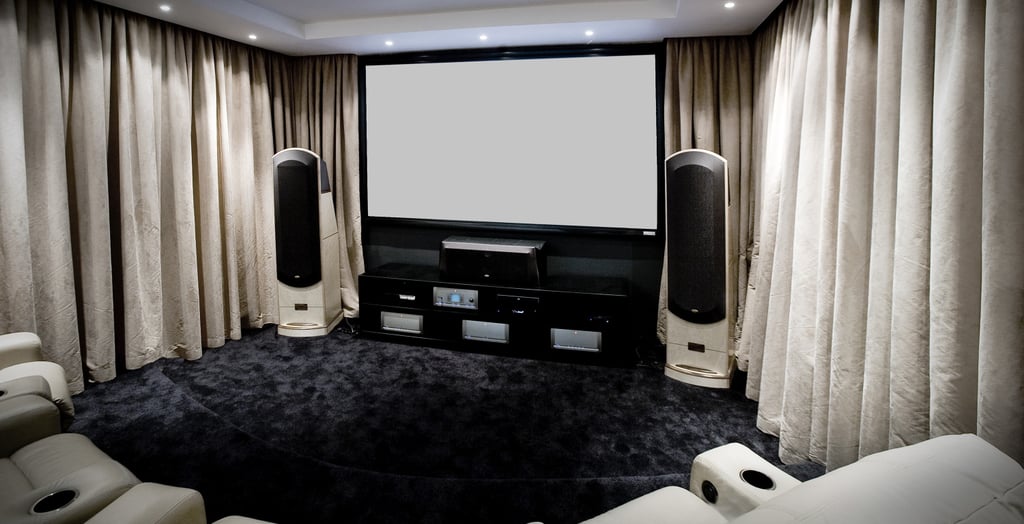 High-end home cinema with a large custom projection screen, plush seating, and premium sound system.