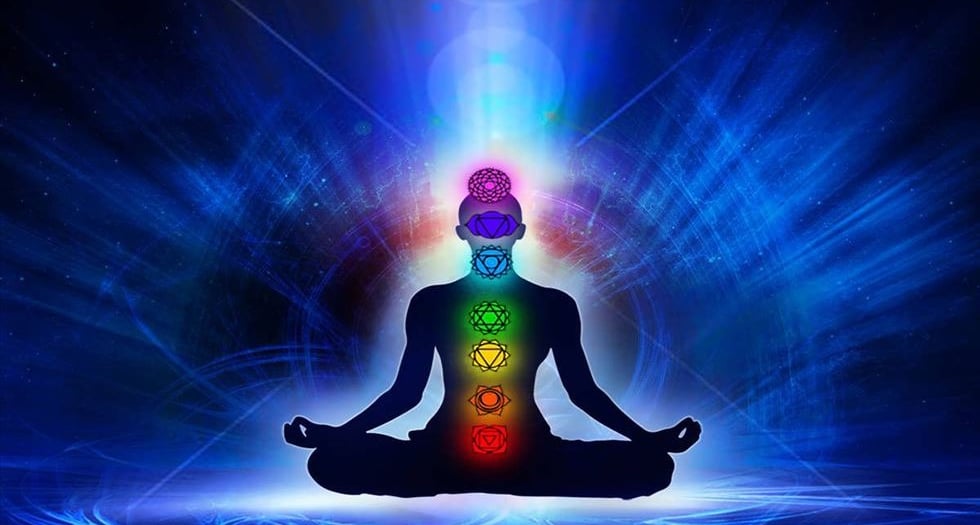 a person sitting in a lotus flower pose having different color aura 
