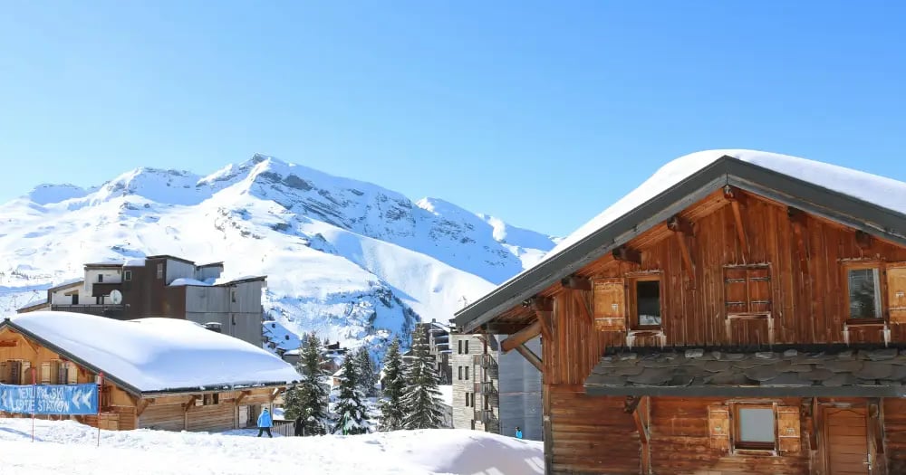 Traditional wooden alpine cabin surrounded by deep snow in a winter mountain setting