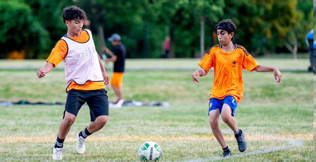 Two MVB F.C. soccer players playing soccer on a grassy field Mississauga