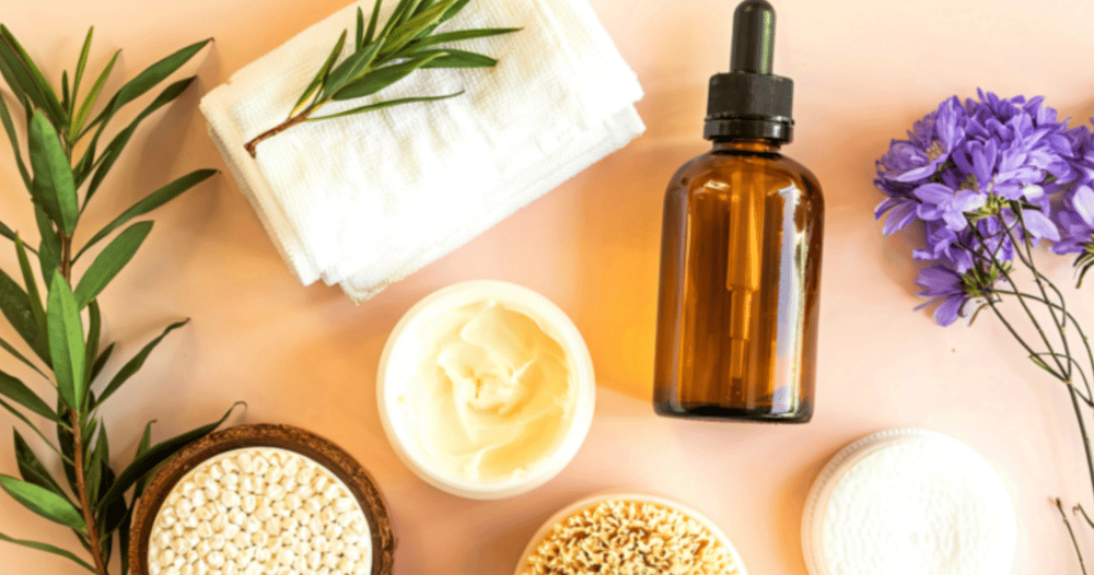 Natural skincare products including a serum dropper bottle, face cream, and body brush on a pink background.