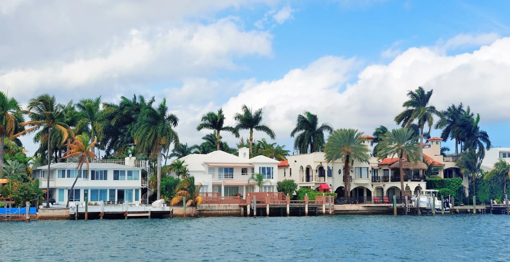Luxury waterfront real estate featuring tropical villas and palm trees along a Florida canal.